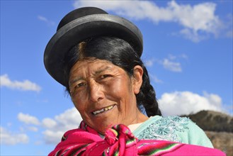 Older indigenous woman with hat smiling at the camera