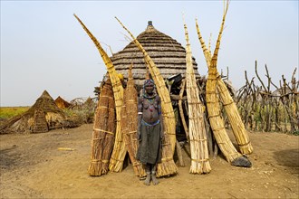 Woman before her hut with ready prepared reeds