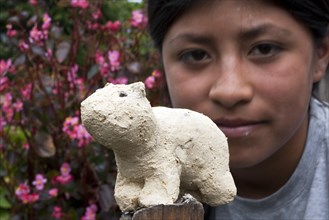 Child with bear statue made of clay