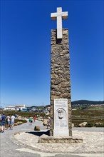 Tourists at the monument with stone cross and information board