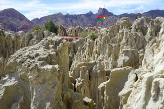 Bizarre rock formations in the Valle de la Luna with flags of la Paz and Bolivia