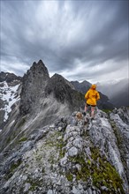 Hiker looking at mountains under dramatic clouds