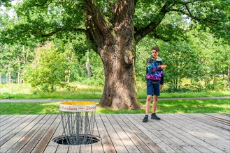 Boy throws a disc at disc golf