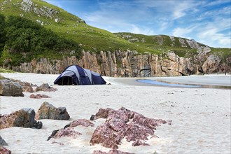 Tent in a bay with rocks and sandy beach
