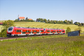 Pesa Link Regional train of Deutsche Bahn DB with church St. Alban in Allgaeu Bavaria in Aitrang