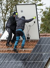 Technicians assembling a photovoltaic system on the roof of a residential building in Markt Swabia