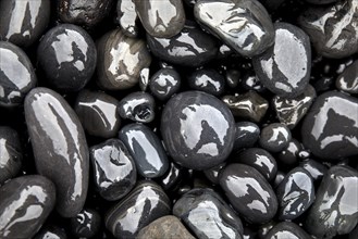 Wet rounded stones with reflection on the beach