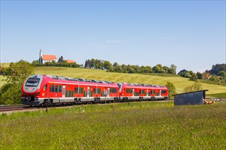 Pesa Link Regional train of Deutsche Bahn DB with church St. Alban in Allgaeu Bavaria in Aitrang