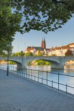 View from the banks of the Rhine along the river promenade to the old town of Basel with the Basel Cathedral