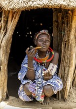 Woman with beauty scars from the Toposa tribe smoking a pipe