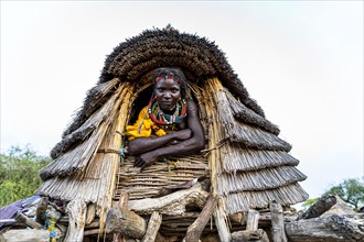 Traditional dressed girl from the Toposa tribe sitting in a grain storage