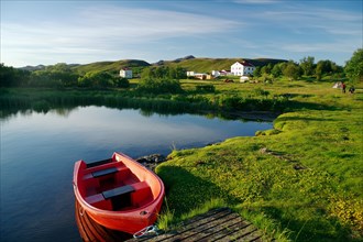 Small red boat on the shore of a lake