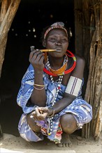 Woman with beauty scars from the Toposa tribe smoking a pipe