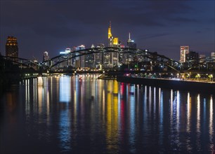 Colourful shining skyline through Deutschherrnbruecke reflected in the Main river during late dusk