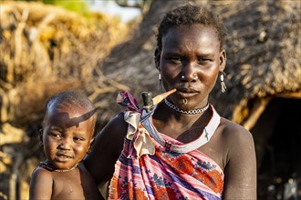 Woman from the Toposa tribe with her baby smoking a pipe