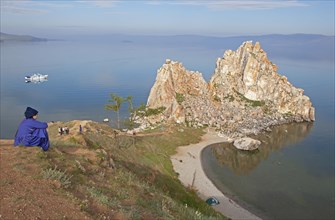 Woman in traditional traditional costume looking at Shaman Rock in Lake Baikal
