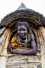 Traditional dressed girl from the Toposa tribe sitting in a grain storage