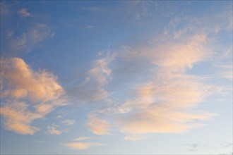 Orange coloured cirrus clouds adorn the blue sky at sunrise