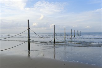 Wooden poles with ropes on the North Sea coast