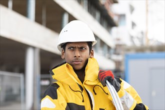 Young technician with helmet and yellow protective jacket working outside