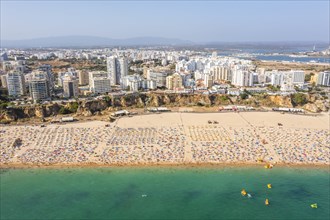 Aerial view of touristic Portimao with wide sandy beach Rocha full of people