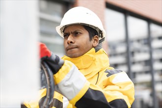 Young technician with helmet and yellow protective jacket working outside