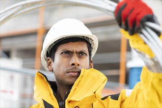 Young technician with helmet and yellow protective jacket working outside