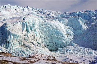 Large ice front of a glacier with crevasses and cracks