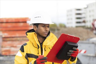 Young technician with helmet and yellow protective jacket working outside