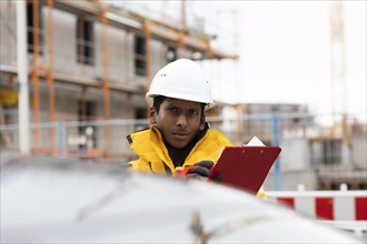 Young technician with helmet and yellow protective jacket working outside