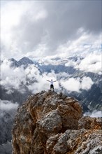 Hiker on a rock stretches arms in the air