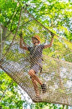 Boy climbing in a net in the climbing forest and high ropes course