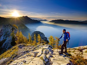 Mountaineer climbing the large Schoberstein in the evening light with view of Attersee and Mondsee