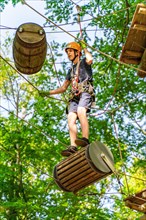 Boy on a floating barrel in the climbing forest and high ropes course