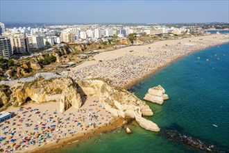 Aerial view of touristic Portimao with wide sandy beach Rocha full of people