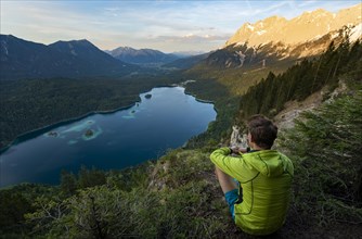 Young man looking over the Eibsee lake at sunset
