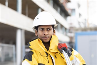 Young technician with helmet and yellow protective jacket working outside