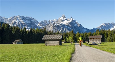 Mountain biker on road through meadow with hay barns
