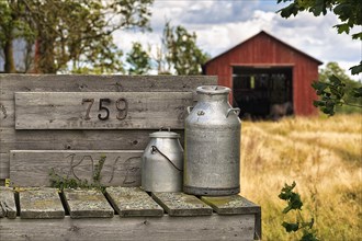 Two milk cans in front of a farm