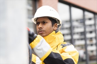 Young technician with helmet and yellow protective jacket working outside