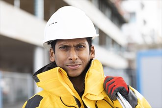 Young technician with helmet and yellow protective jacket working outside