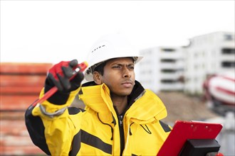 Young technician with helmet and yellow protective jacket working outside