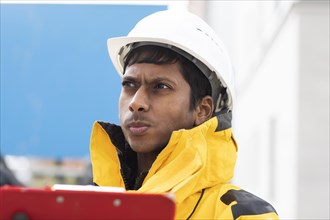 Young technician with helmet and yellow protective jacket working outside