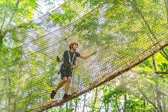 Boy climbing in a net in the climbing forest and high ropes course