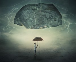 Surrealistic image as a man stand in a foggy street under a huge levitating rock