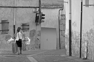 Woman carrying objects through alley in Cuenca