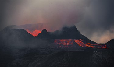 Erupting volcano with lava fountains and lava field