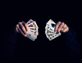 Man's hands holding five playing cards each over