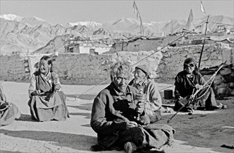 Tibetan refugees turning prayer wheels in front of Himalayan panorama