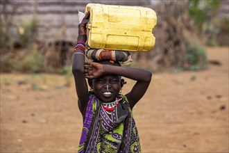 Traditional dressed girl carrying a water container